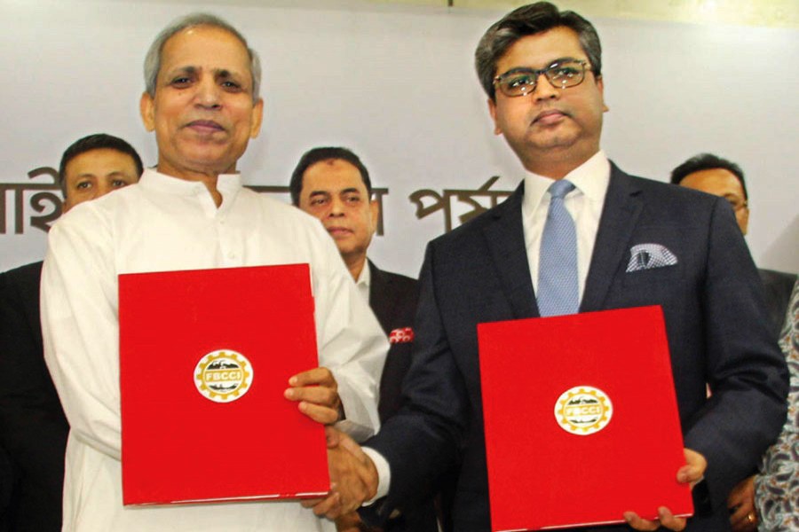 Outgoing president of the FBCCI M Shafiul Islam Mohiuddin handing over the 'FBCCI flag' to newly elected president Sheikh Fazle Fahim at a function held at the FBCCI auditorium in the capital on Sunday