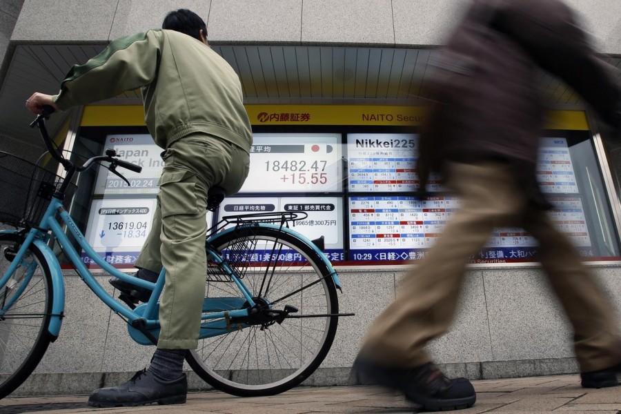 A man riding on a bicycle looks at an electronic board showing the Japan's Nikkei average outside a brokerage in Tokyo, February 24, 2015. Reuters/File Photo