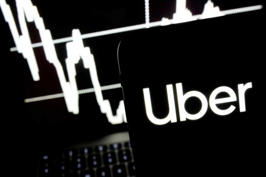 Logo of the Uber is seen on a smartphone screen as a picture of stock exchange graph is displayed on a computer screen in this illustration picture. Reuters