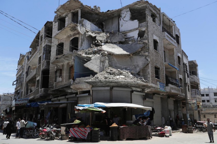 People walk past a damaged building in the city of Idlib, Syria May 25, 2019 - REUTERS/Khalil Ashawi