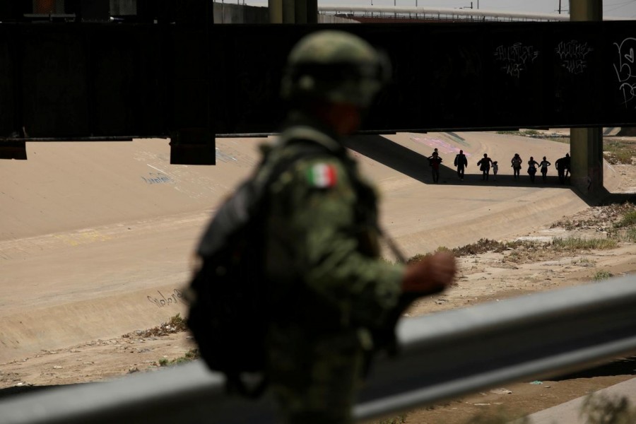 A member of Mexico's National Guard looks at people walking in El Paso, US, Texas after illegally crossing the border, as seen from Ciudad Juarez, Mexico June 21, 2019 - REUTERS/Jose Luis Gonzalez/Files