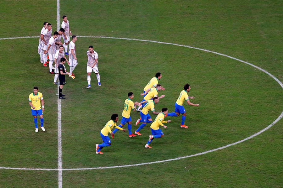 Brazil players celebrate as Paraguay players look dejected after the match — Reuters action image