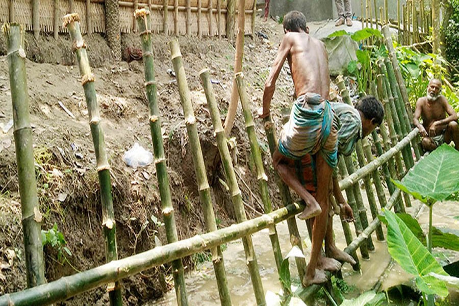 Villagers in Dhunot upazila of Bogura district erecting bamboo fence to save the village protection dam on Saturday	— FE Photo