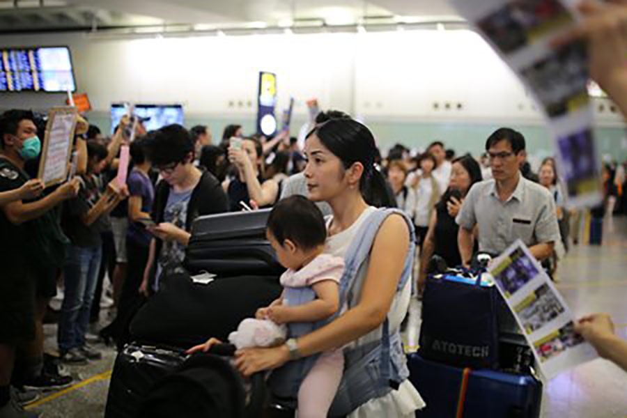 Travelers passing through a crowd of protesters at the Hong Kong International Airport Terminal 1 arrival hall on Friday. -Global Times Photo