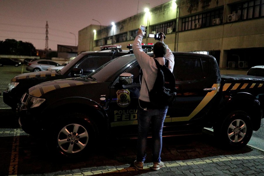 A cameraman records pickup trucks with livery resembling Brazil's federal police inside the DEIC (State Criminal Investigation Department), which were used by thieves during the theft at Guarulhos airport in Sao Paulo, Brazil on July 25, 2019 — Reuters photo