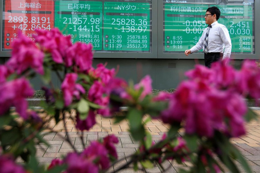 A passerby walks past in front of a stock quotation board outside a brokerage in Tokyo, Japan, May 10, 2019. Reuters/Files