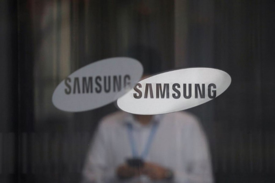 An employee using his mobile phone walks past the logo of Samsung Electronics at its office building in Seoul, South Korea in this undated Reuters photo