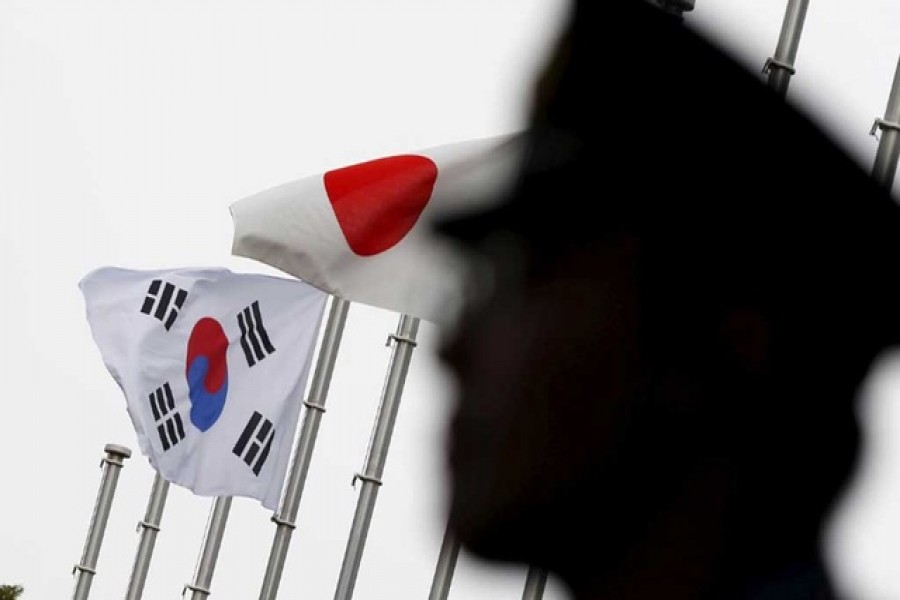 A police officer stands guard near Japan and South Korea national flags at a hotel, where the South Korean embassy in Japan is holding the reception to mark the 50th anniversary of the normalisation of ties between Seoul and Tokyo, in Tokyo, June 22, 2015. Reuters/Files