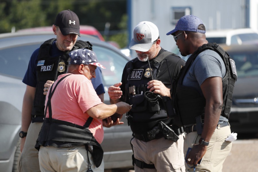 Domingo Candelaria, a registered immigrant, shows federal agents his identification as he prepares to leave the Koch Foods Inc., plant in Morton, Miss., following a raid by U.S. immigration officials, Wednesday, Aug. 7, 2019. The raid, one of several in Mississippi, was part of a large-scale operation targeting owners as well as undocumented employees. (AP Photo/Rogelio V. Solis)