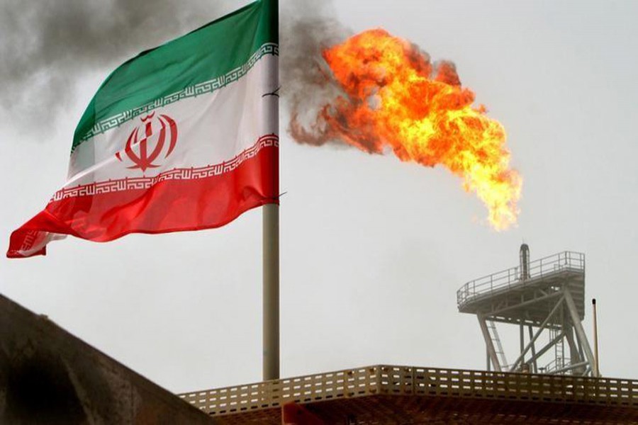 A gas flare on an oil production platform in the Soroush oil fields is seen alongside an Iranian flag in the Persian Gulf, Iran, July 25, 2005. Reuters/File Photo