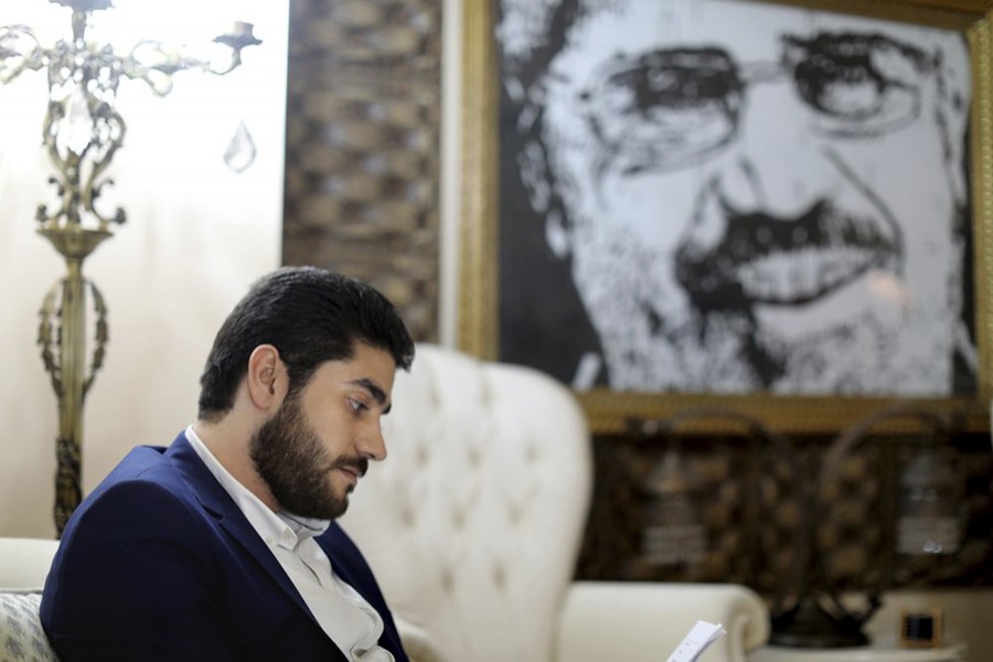 Abdullah Mursi, the youngest son of Egypt’s ousted Islamist President Mohamed Morsi, sits in front of a framed image of his father that was printed on a flag during the 2013 Rabaah al-Adawiya sit-in, at his home in Cairo, Egypt — AP/Files