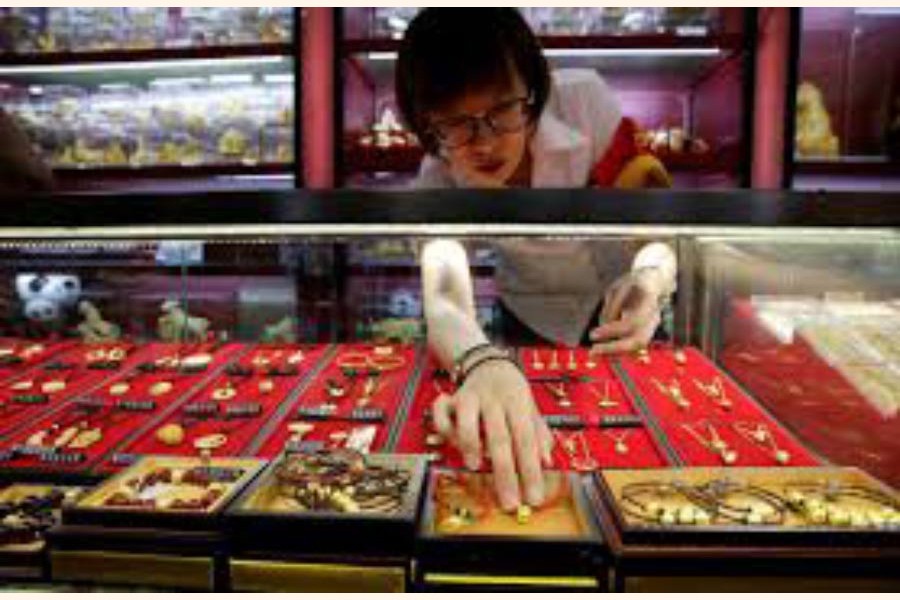 A sales assistant taking out gold ornaments for a customer at Caibai Jewelry store, in Beijing, China                        	— Reuters