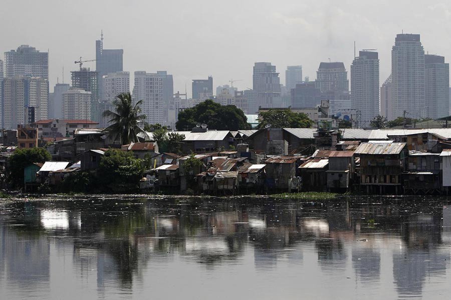 High-rise buildings are seen in the background with slum dwellings in the front, near a polluted river in Manila, the capital of the Philippines. -Reuters file photo