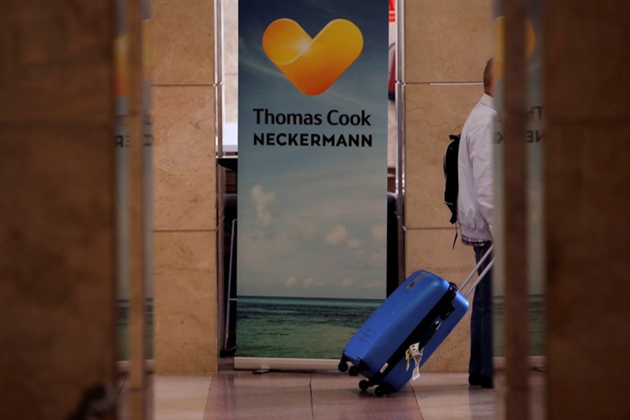 A passenger hauls his luggage past a sign of the collapsed travel firm Thomas Cook at Jerez de la Frontera Airport, Spain on September 23, 2019 — Reuters photo