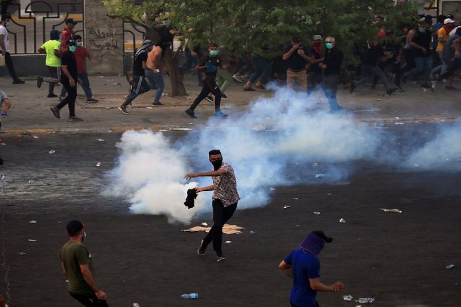 A demonstrator prepares to throw a tear gas canister used by Iraqi security forces as others disperse during a protest over unemployment, corruption and poor public services, in Baghdad, Iraq October 2, 2019 - Reuters