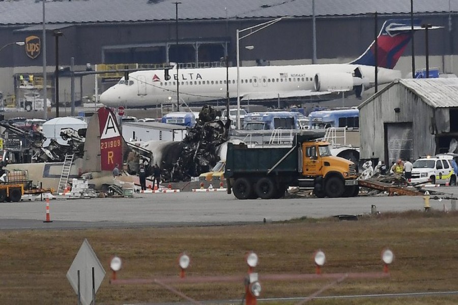 A Delta commercial airline plane taxis to take-off behind investigators at the wreckage of World War II-era bomber plane that crashed at Bradley International Airport in Windsor Locks, Conn., Wednesday, Oct. 2, 2019. (AP Photo/Jessica Hill)