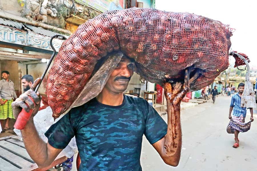 A labourer carrying a sack of rotten onion purchased by a retailer from Shyambazar wholesale market in the city on Friday at a price of Tk 105 per kg — FE photo