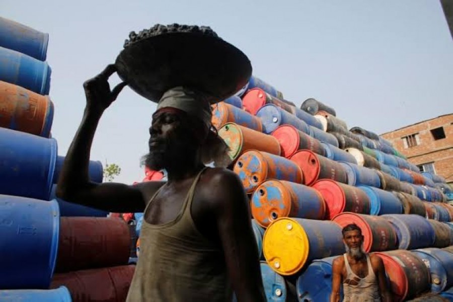 FILE PHOTO: Men work at a godown for storing empty oil drums by Buriganga river in Dhaka, Bangladesh May 18, 2014. REUTERS/Andrew Biraj/File Photo