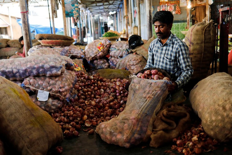 A vendor puts onions in a sack after sorting them at a vegetable market in Mumbai on June 12, 2018 — Reuters/Files