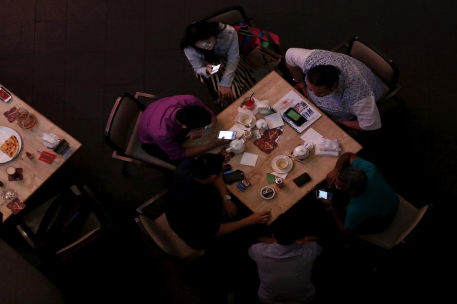 FILE PHOTO: Diners check their phones at a restaurant in the main shopping district of Kuala Lumpur, Malaysia, February 17, 2016. REUTERS/Olivia Harris/File Photo