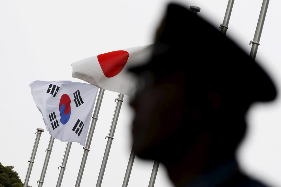 FILE PHOTO: A police officer stands guard near Japan and South Korea national flags at hotel, where South Korean embassy in Japan is holding the reception to mark the 50th anniversary of normalisation of ties between Seoul and Tokyo, in Tokyo June 22, 2015. REUTERS/Toru Hanai