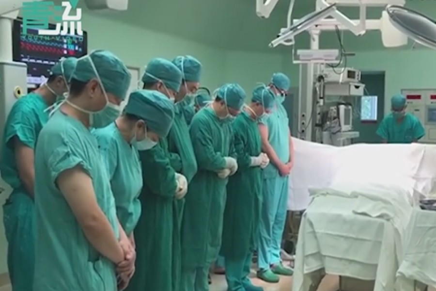 Doctors stand in silent tribute for Man Yu'ang, a two-year-old boy from Beijing whose organs have saved the lives of four people after his accidental death. Photo: Screenshot from the video posted by Beijing Youth Daily.