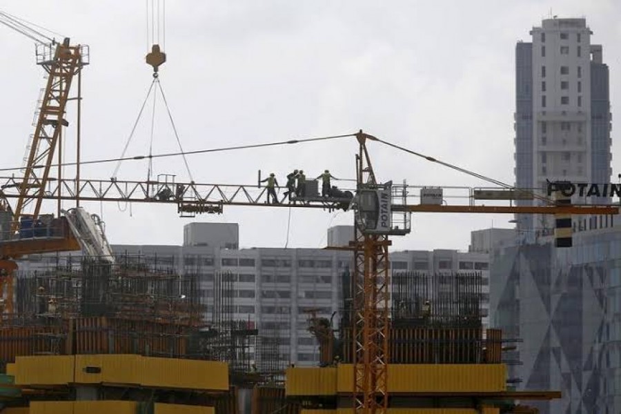 Workers stand on a crane at the construction site of a residential complex in Mumbai, India, May 27, 2015. REUTERS/Shailesh Andrade