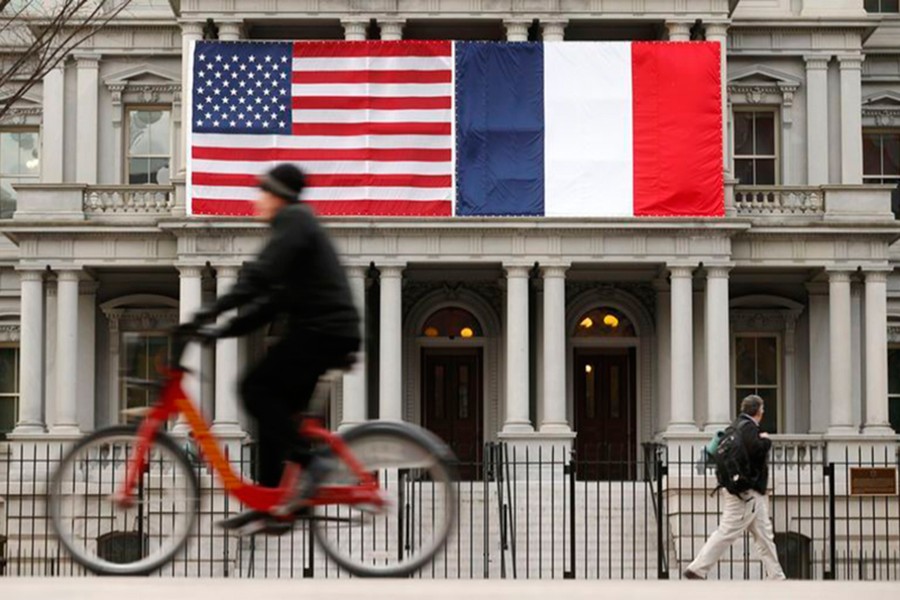 A cyclist passes the US and French flags flying over the Eisenhower Executive Office Building, which houses a majority of offices for White House staff, in Washington on February 10, 2014 — Reuters/Files