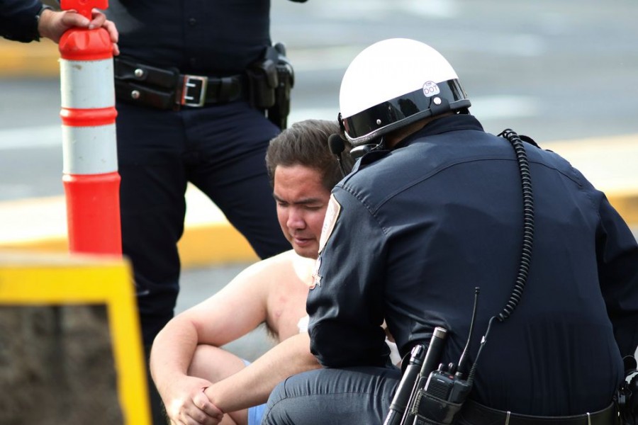 Security forces attend to an unidentified male outside the the main gate at Joint Base Pearl Harbor-Hickam, Wednesday, Dec. 4, 2019, in Hawaii, following a shooting. (AP Photo/Caleb Jones)