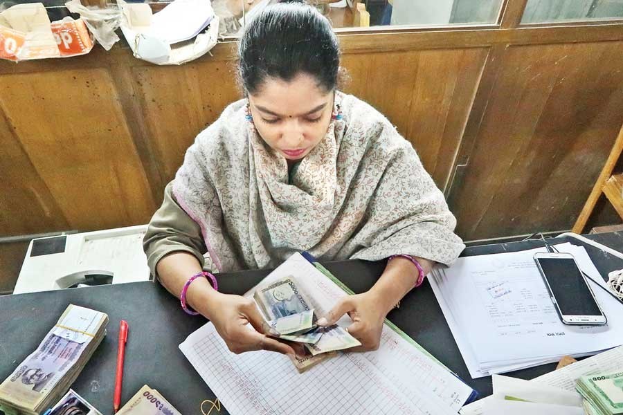 A bank staffer checking notes at a counter of her commercial bank in Dhaka — FE photo