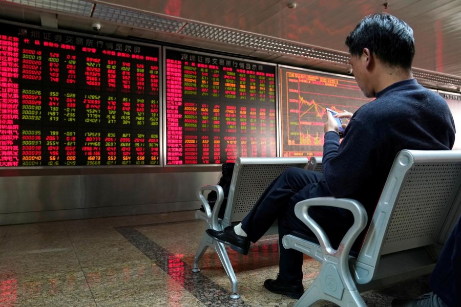 An investor uses his mobile phone in front of a stock quotation board at a brokerage office in Beijing, China, January 03, 2020. Reuters