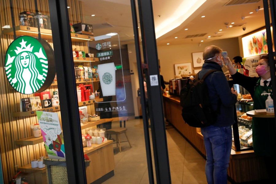 A worker uses a thermometer to check the temperature of a customer as he enters a Starbucks shop as the country is hit by an outbreak of the new coronavirus, in Beijing, China, January 30, 2020. Reuters