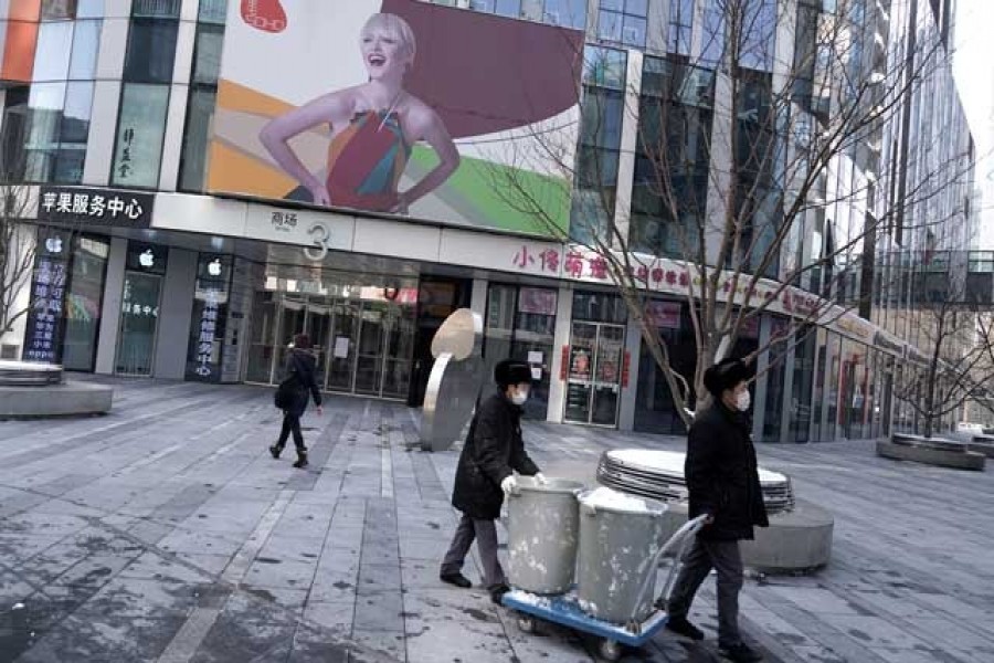 Clean workers move the snow past closed stores at a shopping area, as the country is hit by an outbreak of the new coronavirus, in Beijing, China, February 07, 2020. Reuters