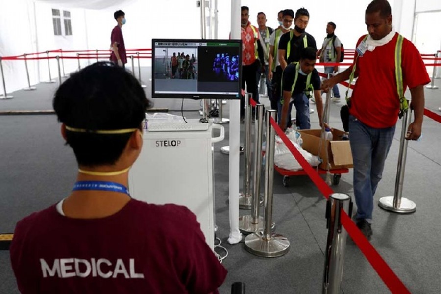 Contractors and workers pass a thermal scanner as part of the coronavirus outbreak precautions during a media preview of the Singapore Airshow in Singapore, February 9, 2020. Reuters