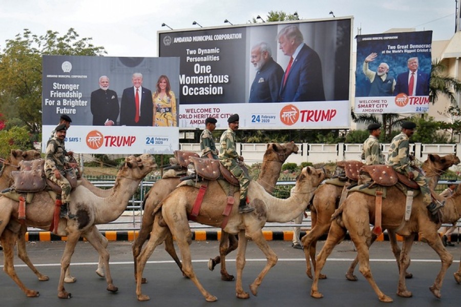 Border Security Force (BSF) soldiers ride their camels past hoardings with the images of India's prime minister Narendra Modi, US president Donald Trump and first lady Melania Trump, as they take part in a rehearsal for a road show ahead of Trump's visit, in Ahmedabad, India, February 21, 2020. Reuters