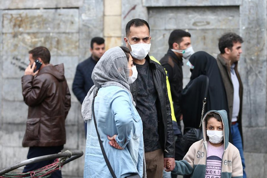 Iranian family wear protective masks to prevent contracting a coronavirus, as they stand at Grand Bazaar in Tehran, Iran on February 20, 2020 — WANA (West Asia News Agency) via Reuters