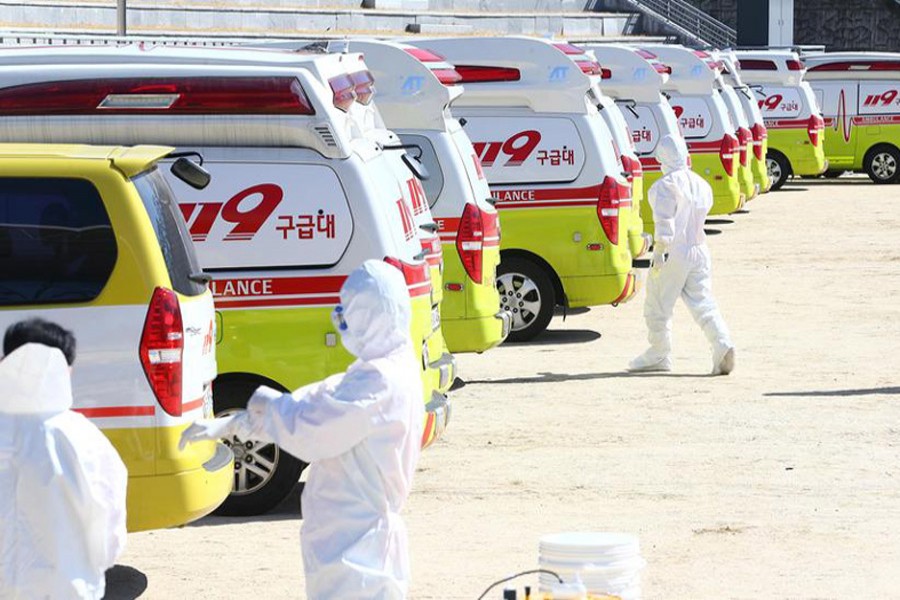 Medical workers get ready as ambulances are parked to transport a confirmed coronavirus patient in Daegu, South Korea, February 23, 2020. Yonhap via Reuters