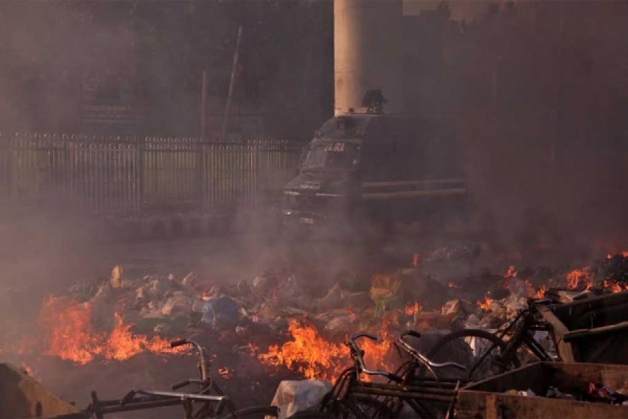 A police vehicle moves past burning debris that was set on fire by demonstrators in a riot affected area after fresh clashes erupted between people demonstrating for and against a new citizenship law in New Delhi, India, February 25, 2020 — Reuters