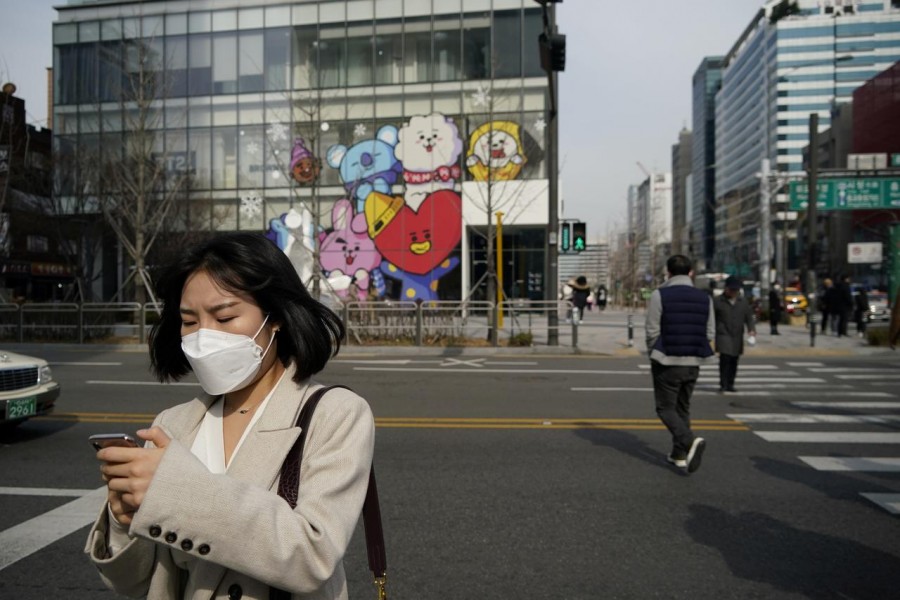 A woman wearing a mask to prevent the coronavirus uses her mobile phone at a shopping district in Seoul, South Korea, February 24, 2020. REUTERS/Kim Hong-Ji