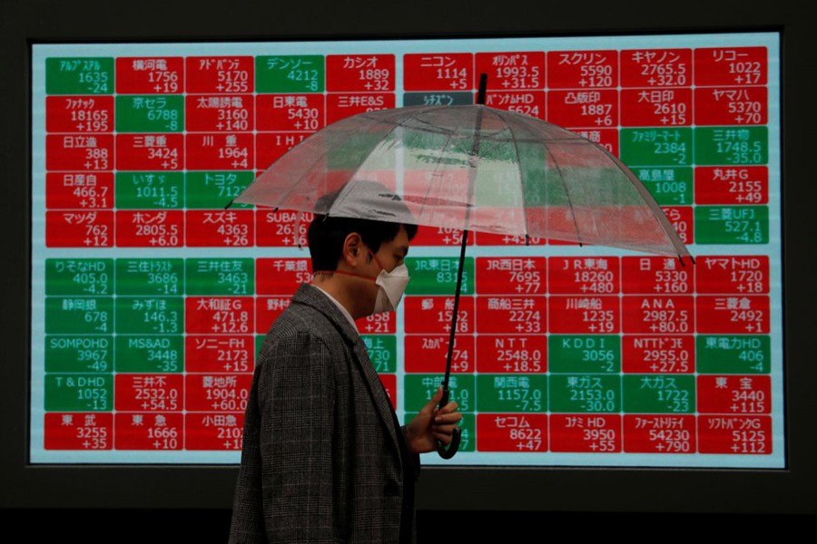 A visitor wearing protective face mask, following an outbreak of the coronavirus, walks past in front of a stock quotation board outside a brokerage in Tokyo, Japan, March 02, 2020 — Reuters