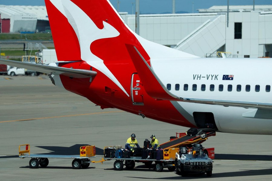 FILE PHOTO: Baggage handlers remove luggage from a Qantas aircraft in Brisbane, Australia, April 7, 2018. REUTERS/Phil Noble/File Photo