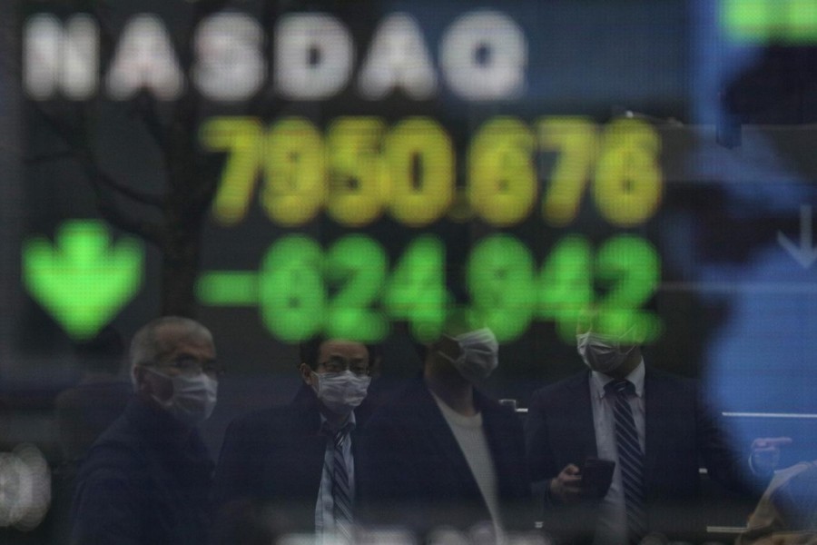 People wearing protective face masks, following an outbreak of the coronavirus disease (COVID-19), are reflected in a screen displaying NASDAQ movements outside a brokerage in Tokyo, Japan on March 10, 2020 — Reuters photo