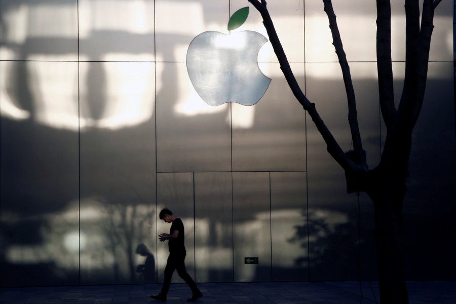 A man uses his phone as he walks past an Apple store in Beijing, China on April 25, 2017 — Reuters/Files