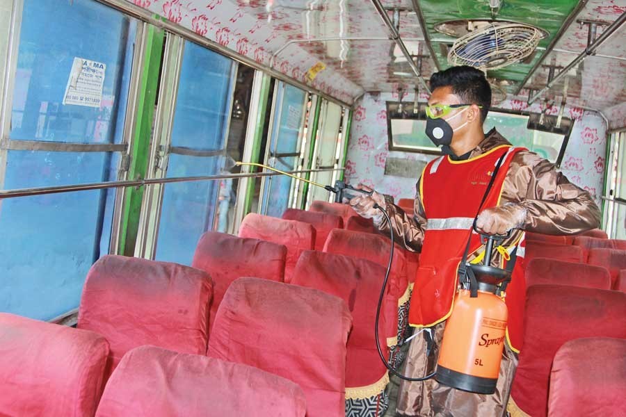 A volunteer of Biddyananda Foundation sanitising a public transport at the NGO's own initiative at Mirpur in the city on Wednesday — FE photo