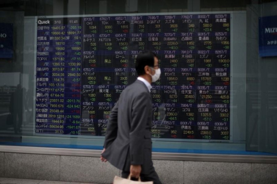 A man wearing protective face mask, following an outbreak of the coronavirus disease (COVID-19), walks in front of a stock quotation board outside a brokerage in Tokyo, Japan, March 10, 2020. — Reuters