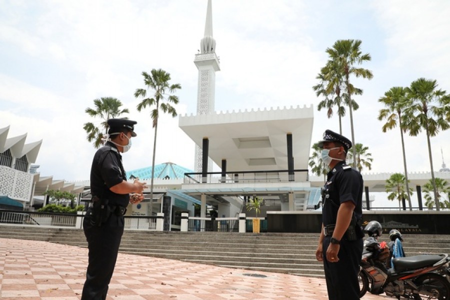 Police officers wearing protective masks stand guard outside National Mosque, after all mosques in the country suspended Friday prayers during the movement control order due to the spread of the coronavirus disease (COVID-19), in Kuala Lumpur, Malaysia Mar 20, 2020. REUTERS