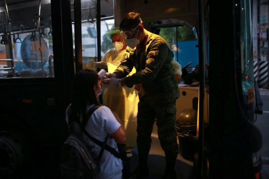 A soldier checks the body temperature of a health worker before entering a free shuttle service following the suspension of mass transportation to contain the spread of coronavirus disease (COVID-19), in Quezon City, Metro Manila, Philippines on March 20, 2020 — Reuters photo