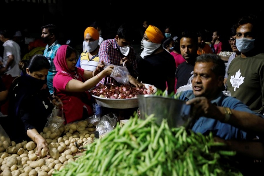 People buy vegetables at a market after India's prime minister Narendra Modi called for a nationwide lockdown starting midnight to limit the spreading of coronavirus disease (COVID-19), in New Delhi, India, March 24, 2020. — Reuters