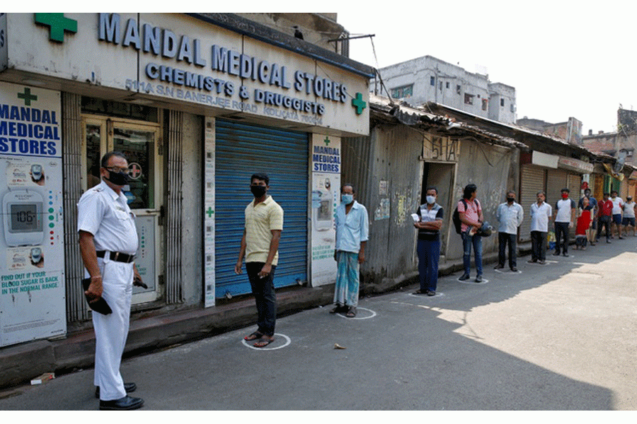 People look on as they stand in circles drawn to maintain safe distance while waiting to buy medicine during a 21-day nationwide lockdown to limit the spreading of Coronavirus disease (COVID-19), in Kolkata, India, Mar 26, 2020. REUTERS