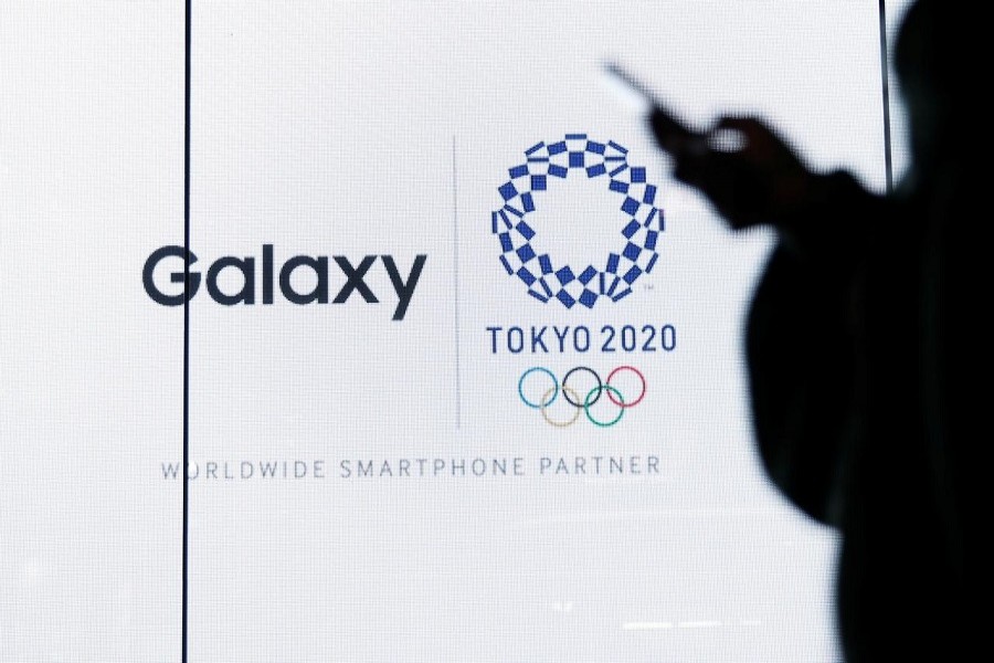 A woman uses her smartphone as an electric screen displaying logos of Tokyo 2020 Olympic Games and Galaxy, a brand name of mobile computing devices by Samsung Electronics and worldwide smartphone partner for the Games, at Galaxy Harajuku in Tokyo, Japan, March 26, 2020. — Reuters